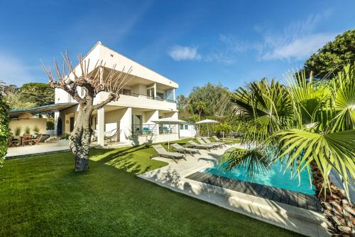 een huis met een zwembad en een tuin met palmbomen bij Villa Montfleuri, vieille ville à pieds, vue mer, piscine, 8 pers in Sainte-Maxime