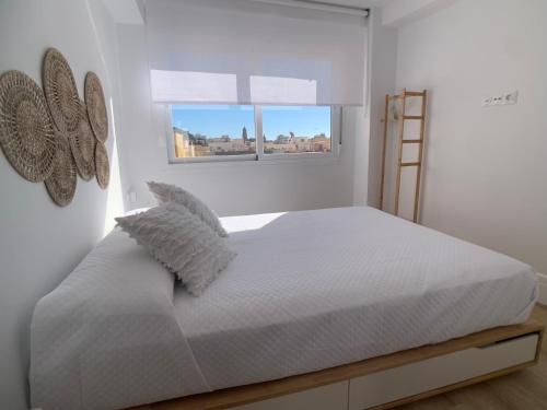 ein weißes Schlafzimmer mit einem Bett und zwei Fenstern in der Unterkunft Ático Mármoles - Centro Málaga in Málaga