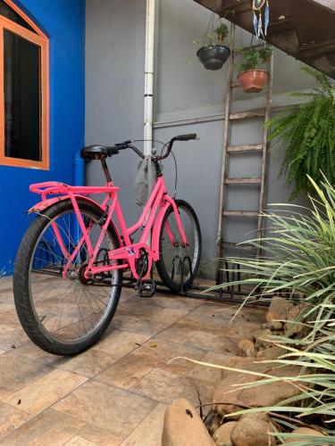 a pink bike parked next to a garage at Fica, Vai ter Bolo Hostel in Itajaí