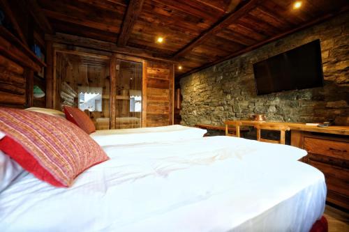 a bedroom with a large white bed with a stone wall at Café Quinson Relais de Charme in Morgex