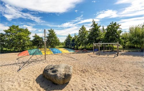 a playground with two swings and a rock in the sand at Lovely Home In Tranekær in Tranekær