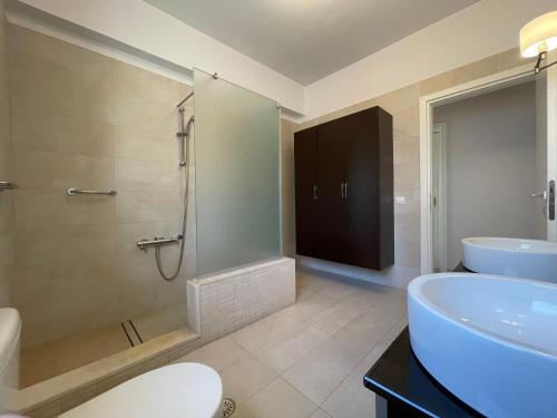 a bathroom with a shower and a tub and a sink at Luxury Villa Loutraki with private heated pool in Loutraki