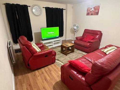 a living room with red furniture and a flat screen tv at JustAlf Facilities-Spacious 2-bed apartment in Thamesmead, Greenwich in London