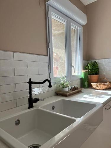 - un grand évier blanc dans la cuisine avec une fenêtre dans l'établissement Au mas des glycines - Gîte La tropézienne - 5 personnes, à Camaret-sur-Aigues