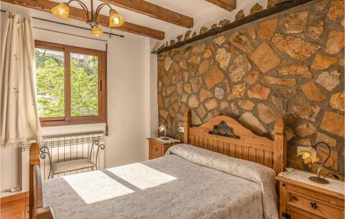 1 dormitorio con pared de piedra, cama y ventana en 1 Bedroom Awesome Home In Mecina Bombarn, en Mecina Bombarón