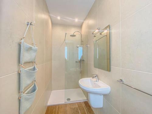 La salle de bains blanche est pourvue d'un lavabo et d'une douche. dans l'établissement Entire Studio Apartment in Sliema 2A By Solea, à Sliema