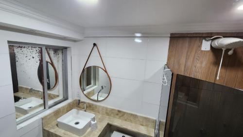een badkamer met een wastafel en 2 spiegels aan de muur bij FLAT Jardim de Alah - Frente Praia in Salvador