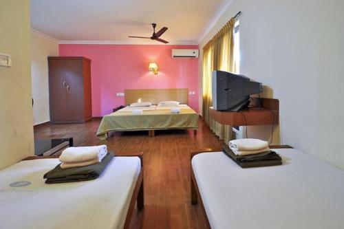 Habitación con 2 camas y TV de pantalla plana. en Hotel Srinivas, en Kochi