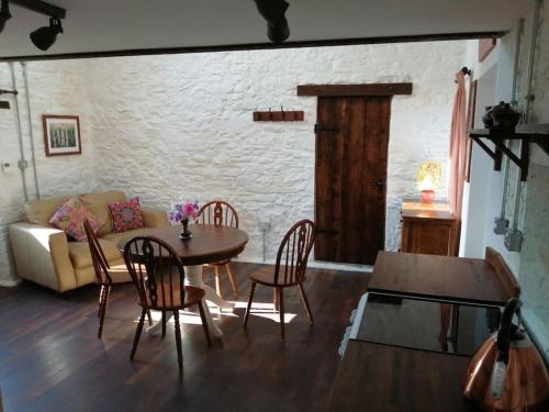 a living room with a table and chairs and a couch at Converted rural stone cottage, Swansea in Swansea