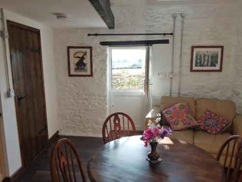 a living room with a table and a couch at Converted rural stone cottage, Swansea in Swansea