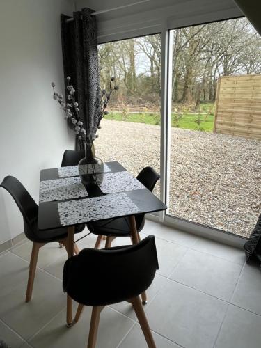une salle à manger avec une table et des chaises et une fenêtre dans l'établissement La petite maison de Kerguiniou, à Glomel