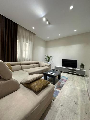 un soggiorno con divano e TV a schermo piatto di Brilant Apartament a Tirana
