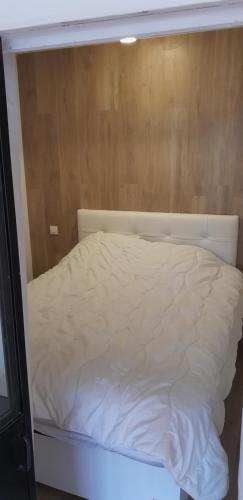 - un lit blanc dans une chambre dotée d'un mur en bois dans l'établissement Appartement 2 ch 40 m2 au pied des pistes de ski, à Enchastrayes