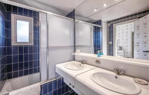 W wyłożonej niebieskimi kafelkami łazience znajduje się umywalka i lustro. w obiekcie Pet Friendly Home In Breda With Kitchen w mieście Breda