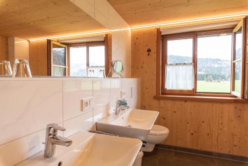 a bathroom with a sink and a toilet and windows at Ferienwohnungen Weiler in Oberstdorf