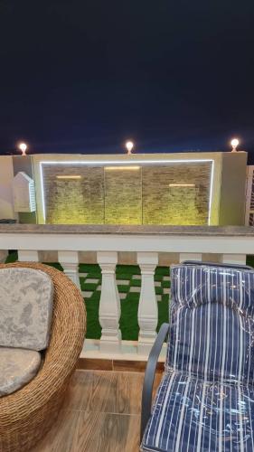 uma cadeira e uma cadeira numa varanda à noite em سمارت شالية:Smart Chalet em Salalah