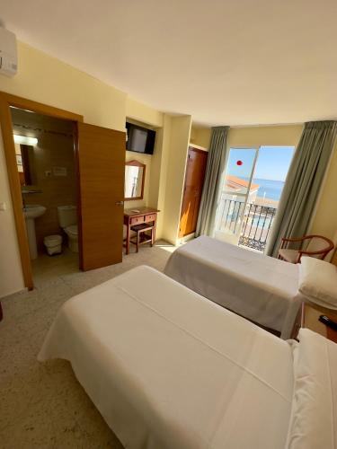 a hotel room with two beds and a balcony at Hotel Cabello in Torremolinos