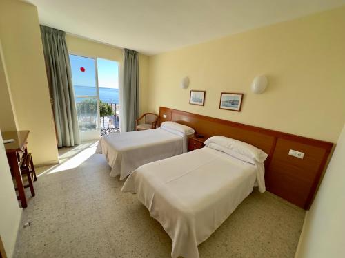 pokój hotelowy z 2 łóżkami i oknem w obiekcie Hotel Cabello w mieście Torremolinos