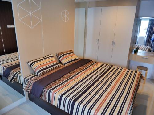 a bedroom with a bed with a striped comforter at Triogems appartamento nuovo affitto mensile in Jomtien Beach