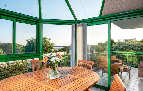 une véranda avec une table en bois et un vase de fleurs dans l'établissement Nice Home In Guidel With Wifi, à Guidel
