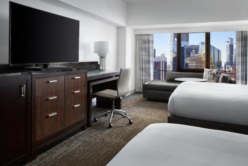 a hotel room with a bed and a desk with a television at New York Marriott Marquis in New York