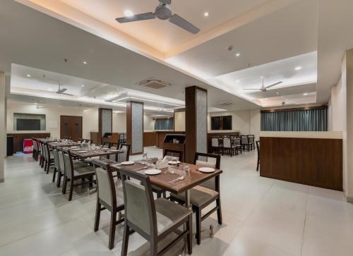 uma sala de jantar com uma mesa longa e cadeiras em Hotel Aaradhya Adorer em Kudāl