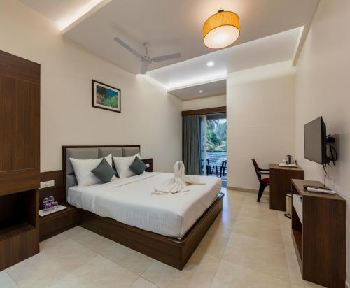 a bedroom with a bed and a desk and a television at Hotel Aaradhya Adorer in Kudal