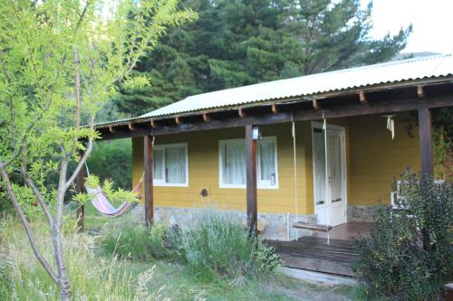 una pequeña casa amarilla con porche y porche en La Colorida en Lago Puelo