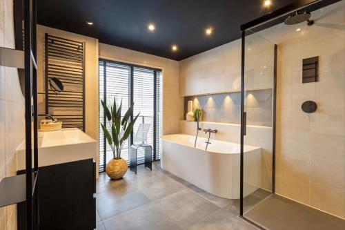La salle de bains est pourvue d'une baignoire, d'un lavabo et d'une douche. dans l'établissement Hotel Hogerhuys - adults only, à Noordwijk aan Zee