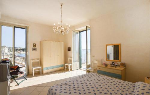 Schlafzimmer mit einem Bett, einem Spiegel und Fenstern in der Unterkunft Cozy Home In Sampieri With House A Panoramic View in Sampieri