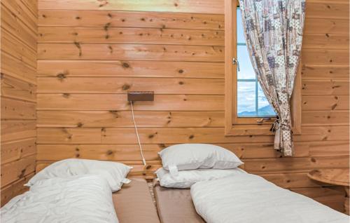 two beds in a room with wooden walls and a window at Nice Home In Sjernarøy With Wifi in Sjernarøy