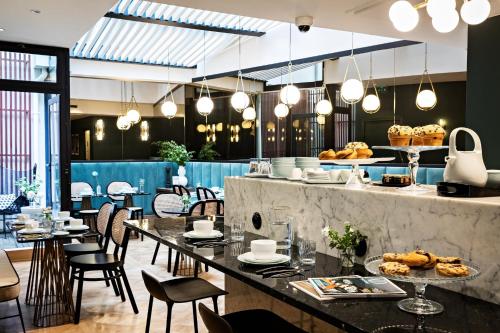 パリにあるHoliday Inn Paris Elysées, an IHG Hotelのテーブルと椅子のあるレストラン、食べ物を取り揃えたカウンター