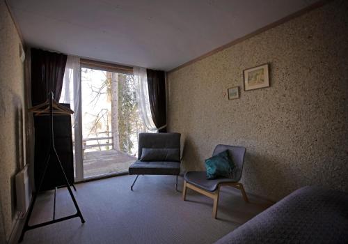 a living room with two chairs and a window at Kempings Ozolkalns in Cēsis