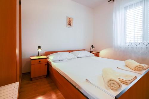a bedroom with a white bed with towels on it at Apartments Katarina k in Malinska