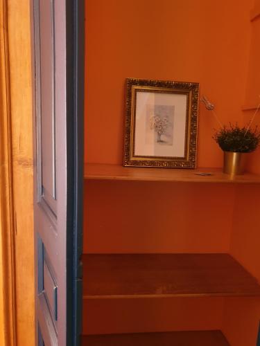 a hallway with an orange wall with a shelf and a picture at Albergo Bergagna in Pont Canavese