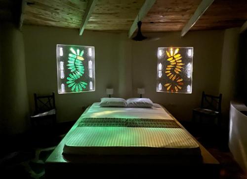 a bedroom with a large bed with two stained glass windows at Bottle Cottage in Shimoni