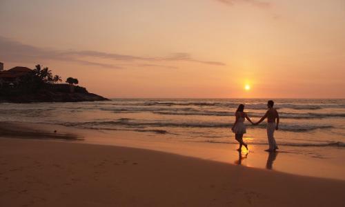 a couple standing on the beach watching the sunset at Jetwing Saman Villas, A Luxury Reserve - Adults Only in Bentota