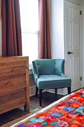 a bedroom with a blue chair and a window at La Posada in Milford