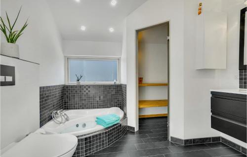 a bathroom with a tub and a toilet and a sink at Holiday Home Strandgården in Sæby