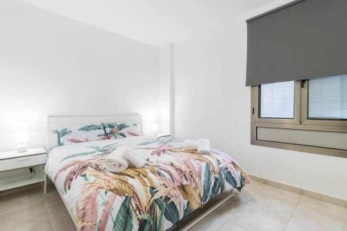 1 dormitorio con 1 cama con una manta colorida y una ventana en La Cicer Beach Artament en Las Palmas de Gran Canaria