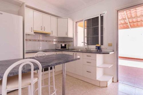 a kitchen with white cabinets and a table and chairs at Villa Mar Deluxe in Castillo del Romeral