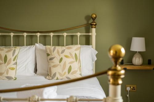 a bedroom with a bed with white pillows and a gold pole at White Hart Inn in Blythburgh
