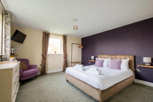 a bedroom with a large bed and a purple wall at White Hart Inn in Blythburgh
