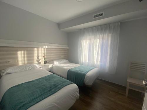 a hotel room with two beds and a window at Casa Rural Villa María in Navahermosa