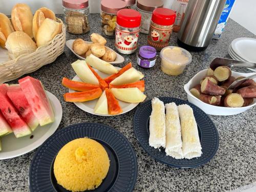 a table with plates of food and bowls of fruit at Studio Universitário in Jacobina