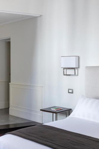 a white bedroom with a bed and a table at Hotel Scalinata Di Spagna in Rome