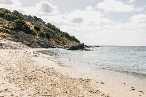 a beach with rocks and the ocean on a cloudy day at Falkensteiner Resort Capo Boi in Villasimius