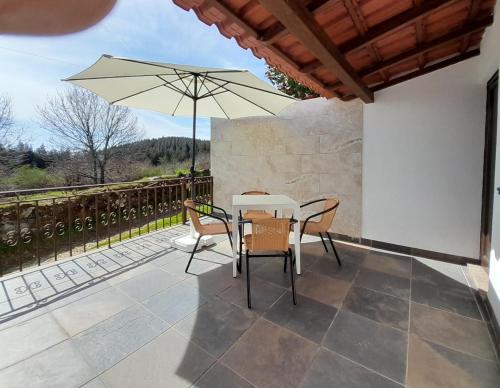 a patio with a table and chairs and an umbrella at Casa Elizabeth in Pedrógão Grande