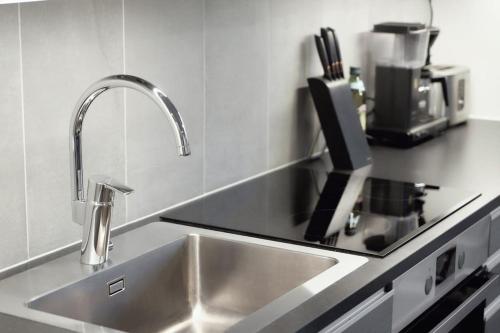 a kitchen sink with a faucet on a counter at Norden Homes Castle Harbour Apartment in Turku