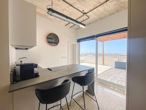 a kitchen with a counter with two chairs and a sink at Valletta Vista Penthouse Where Sky Meets History By Solea in Sliema